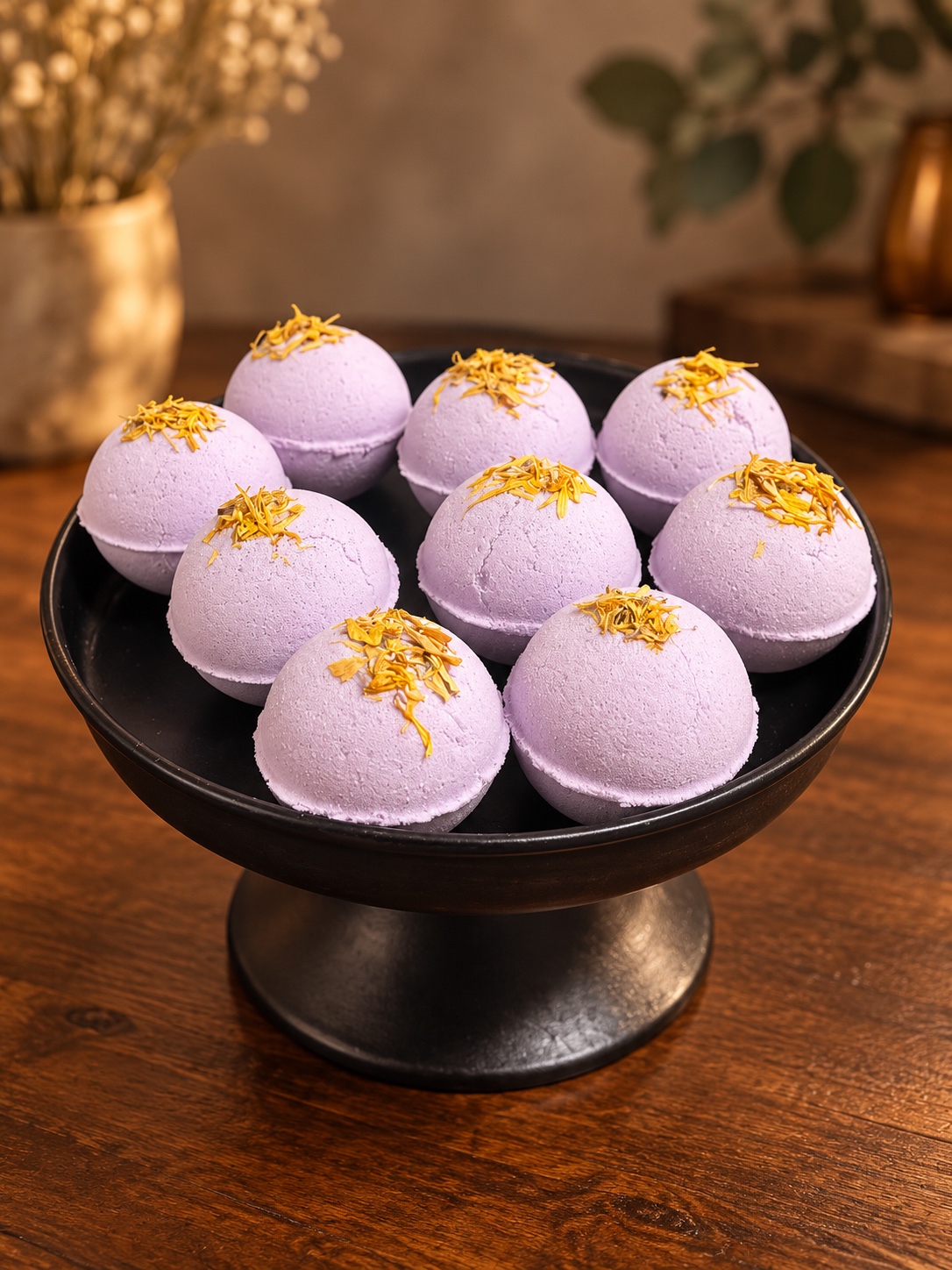 Purple Sacred Ground bath bombs topped with golden botanicals on a black pedestal